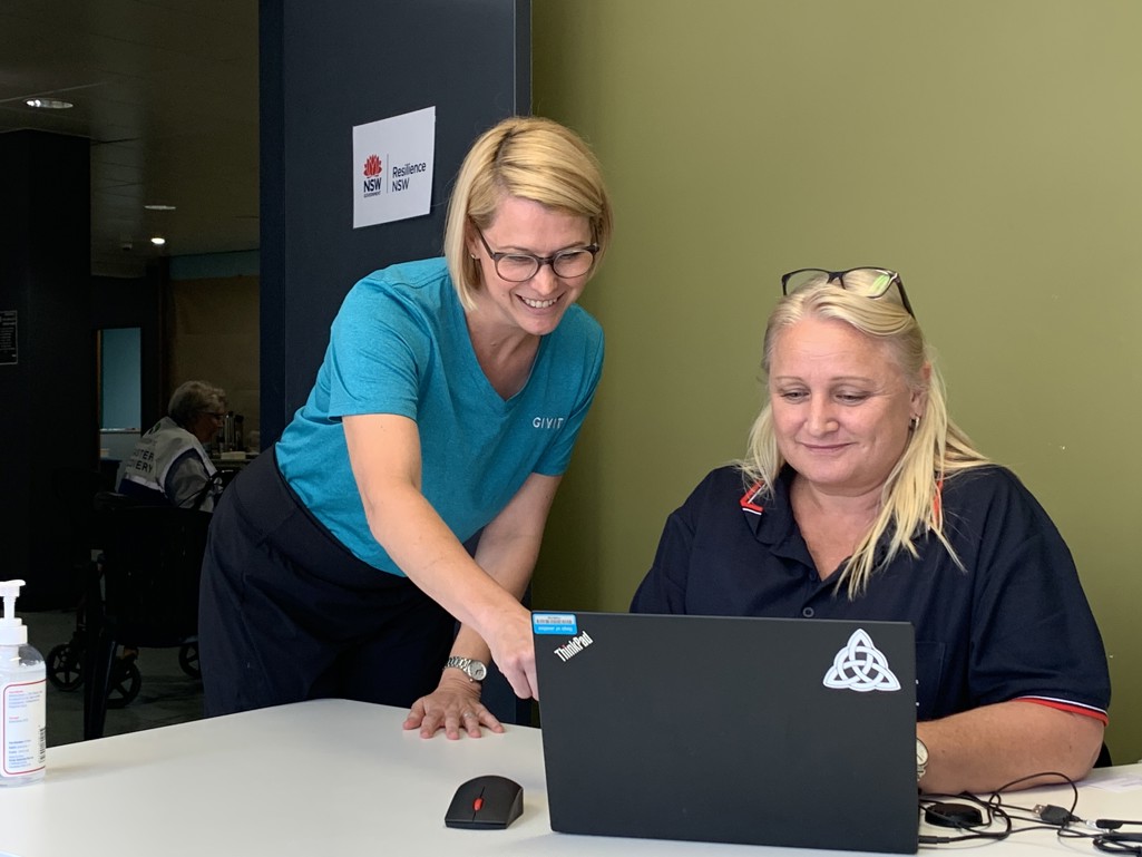 A female GIVIT employee showing a female supporter worker how to use GIVIT on her laptop.